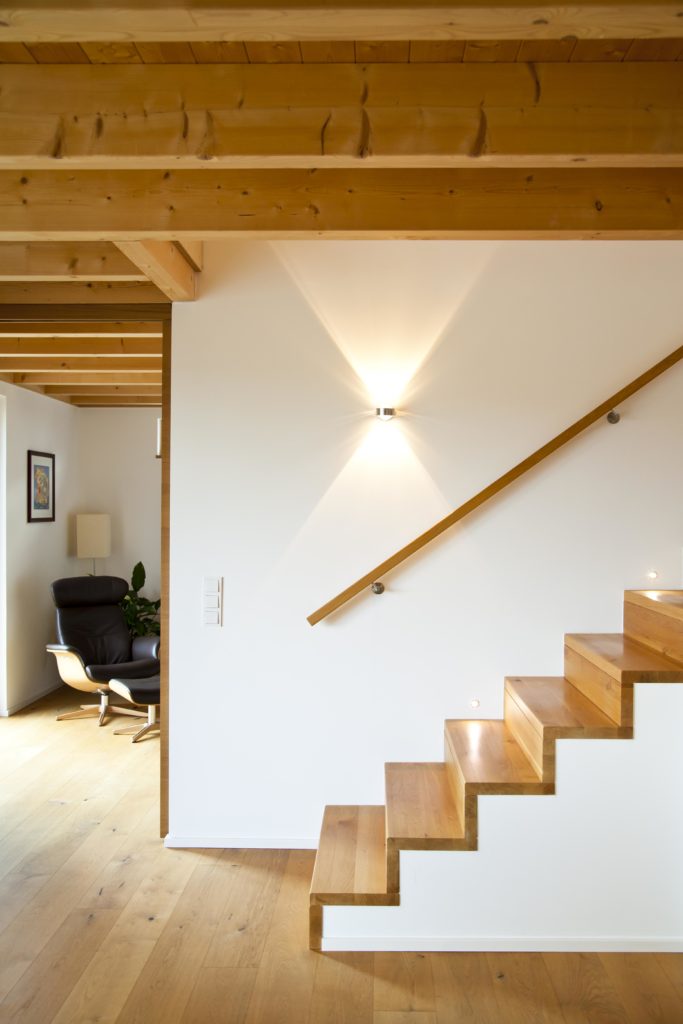 Holzdecke im Erdgeschoss und passende Holztreppe mit eckigem Handlauf aus Holz