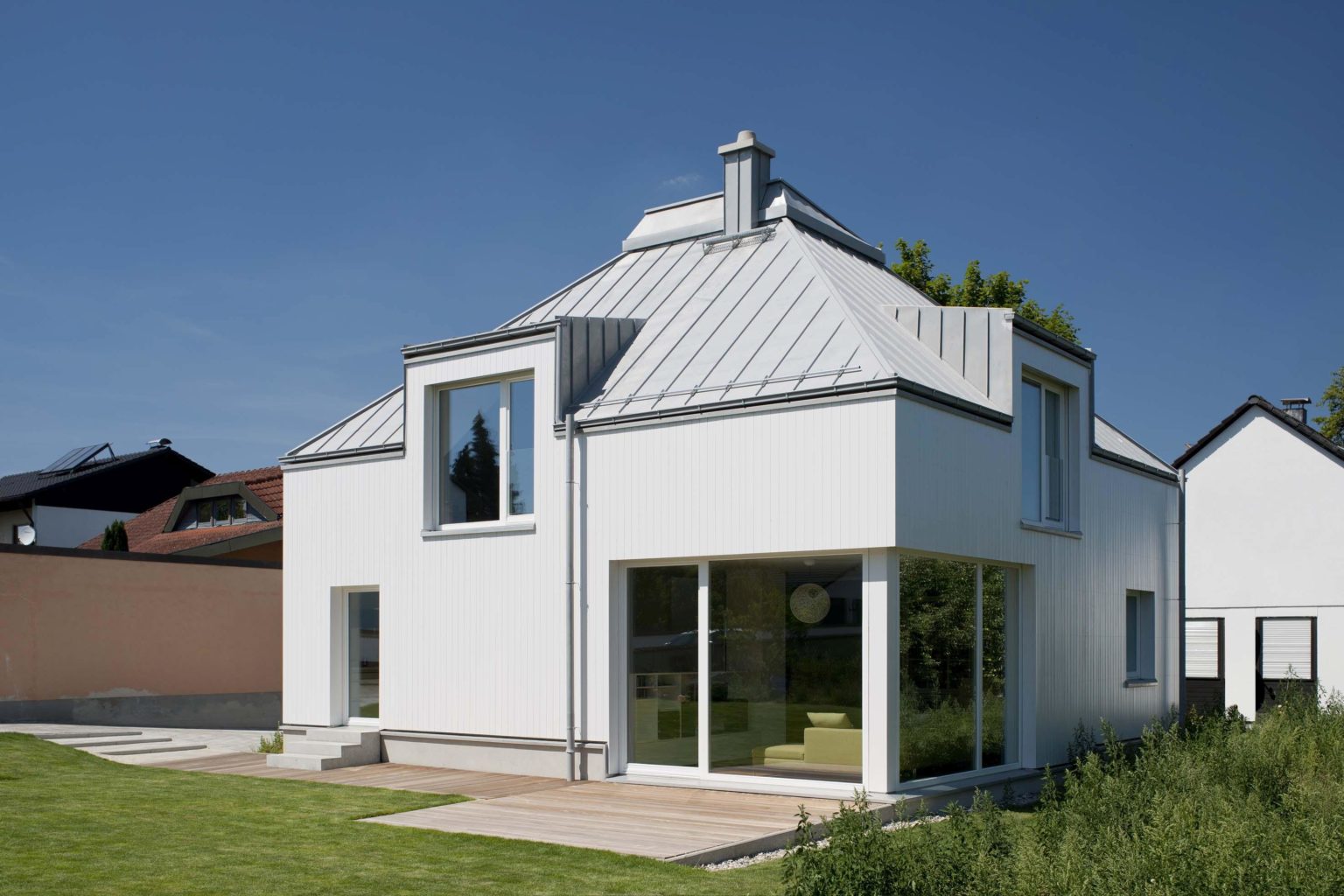 Außenansicht Holzhaus, weiße Holzfassade, quadratischer Grundriss und Zeltdach